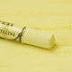 A close-up of a yellow Sennelier extra soft pastel. on the same coloured background, with the colour information printed on the paper wrap.
