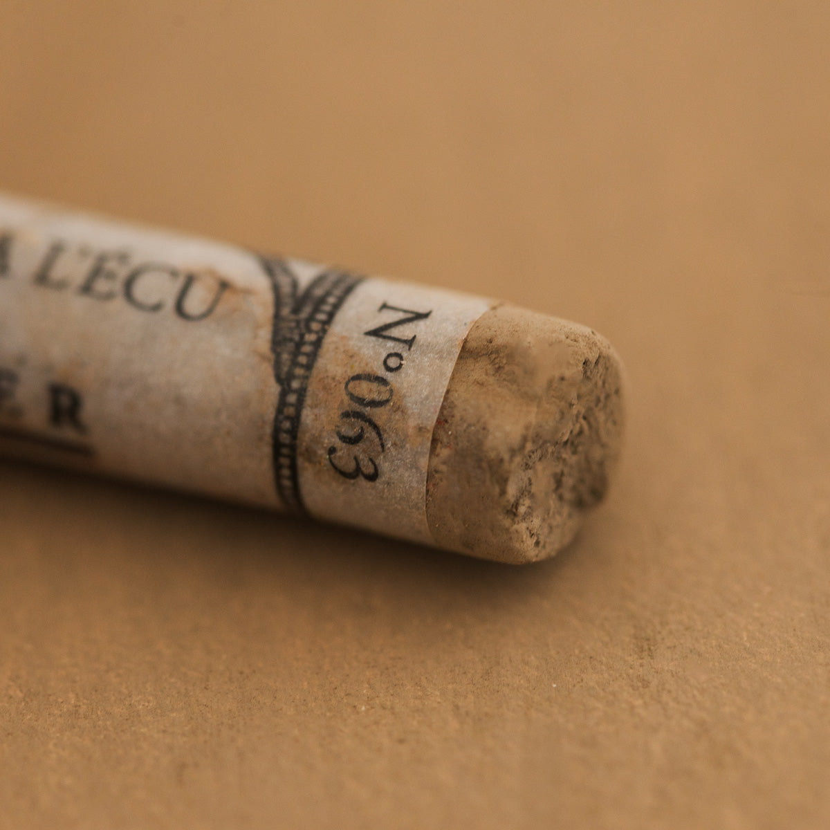 A close-up of a brown Sennelier extra soft pastel with the colour information printed on the paper wrap.