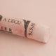 A close-up of a white Sennelier extra soft pastel. on the same coloured background, with the colour information printed on the paper wrap.