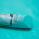 A close-up of a green Sennelier extra soft pastel. on the same coloured background, with the colour information printed on the paper wrap.