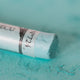 A close-up of a green Sennelier extra soft pastel. on the same coloured background, with the colour information printed on the paper wrap.