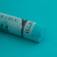 A close-up of a green Sennelier extra soft pastel. on the same coloured background, with the colour information printed on the paper wrap.