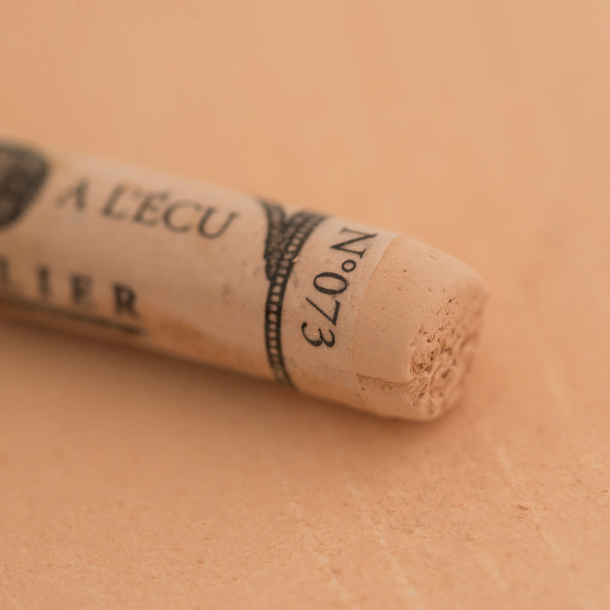 A close-up of a Sennelier extra soft pastel on a white background with the colour information printed on the paper wrap.