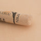 A close-up of a Sennelier extra soft pastel on a white background with the colour information printed on the paper wrap.