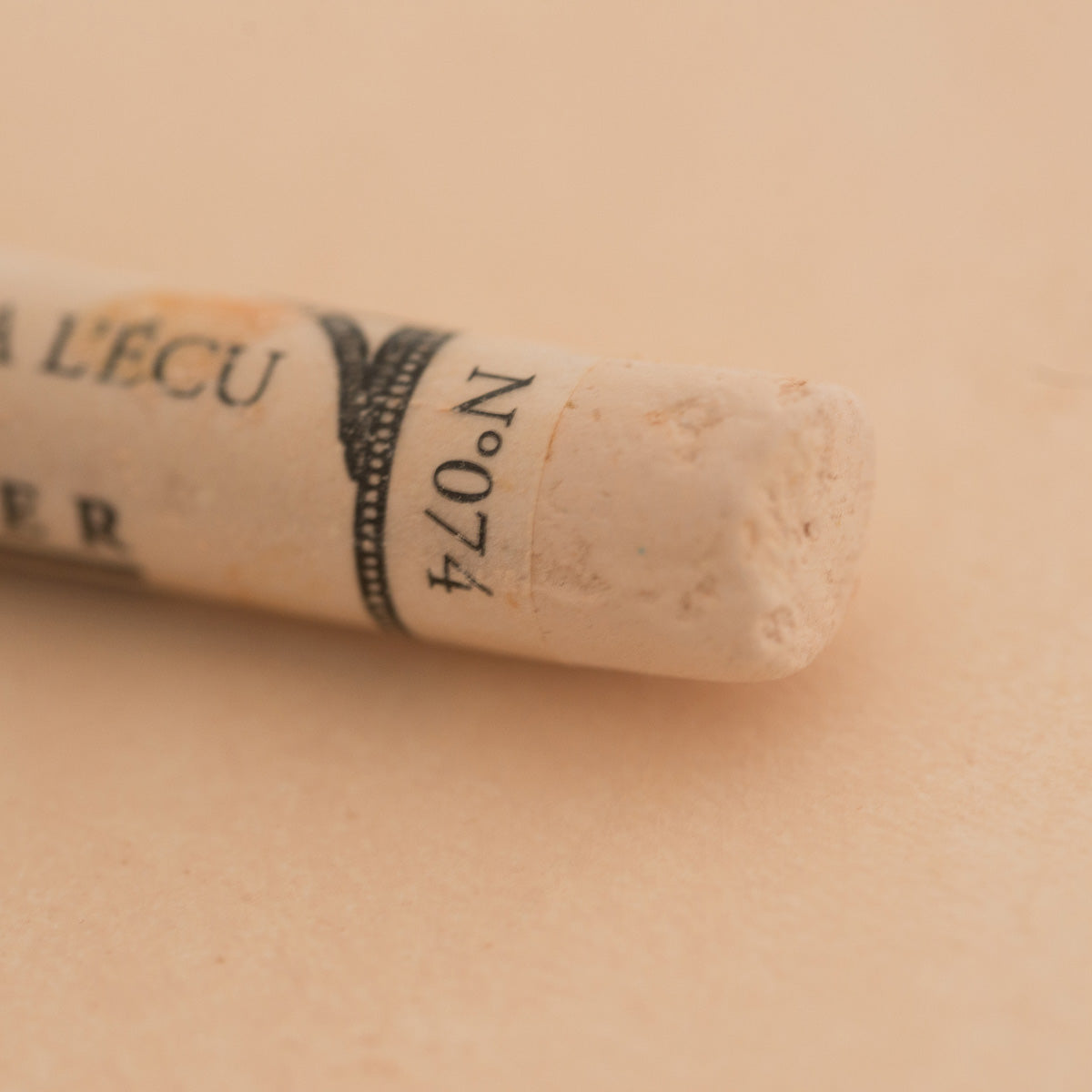 A close-up of a Sennelier extra soft pastel on a white background with the colour information printed on the paper wrap.
