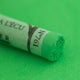 A close-up of a bright green Sennelier extra soft pastel. on the same coloured background, with the colour information printed on the paper wrap.