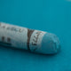 A close-up of a blue Sennelier extra soft pastel on the same coloured background, with the colour information printed on the paper wrap.