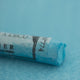 A close-up of a blue Sennelier extra soft pastel on the same coloured background, with the colour information printed on the paper wrap.