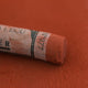 A close-up of a brown Sennelier extra soft pastel with the colour information printed on the paper wrap.