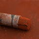 A close-up of a brown Sennelier extra soft pastel with the colour information printed on the paper wrap.