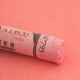 A close-up of a pale red Sennelier extra soft pastel. on the same coloured background, with the colour information printed on the paper wrap.