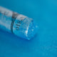 A close-up of an iridescent blue Sennelier extra soft pastel. on the same coloured background, with the colour information printed on the paper wrap.