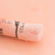 A close-up of a pale orange Sennelier extra soft pastel on the same coloured background, with the colour information printed on the paper wrap.