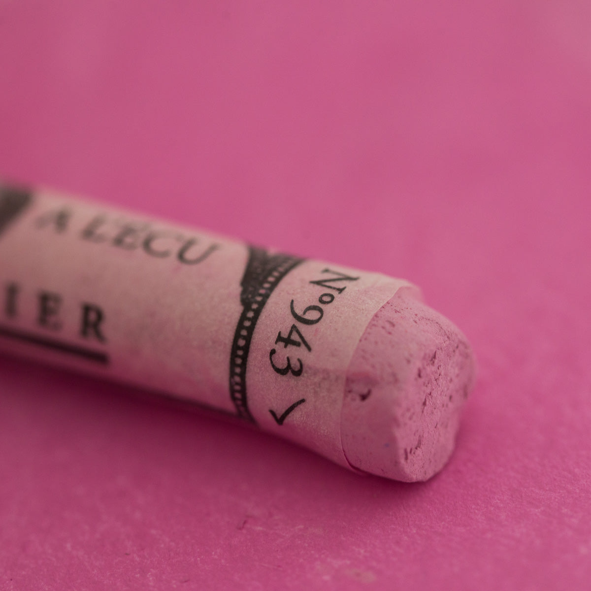 A close-up of a purple Sennelier extra soft pastel. on the same coloured background, with the colour information printed on the paper wrap.