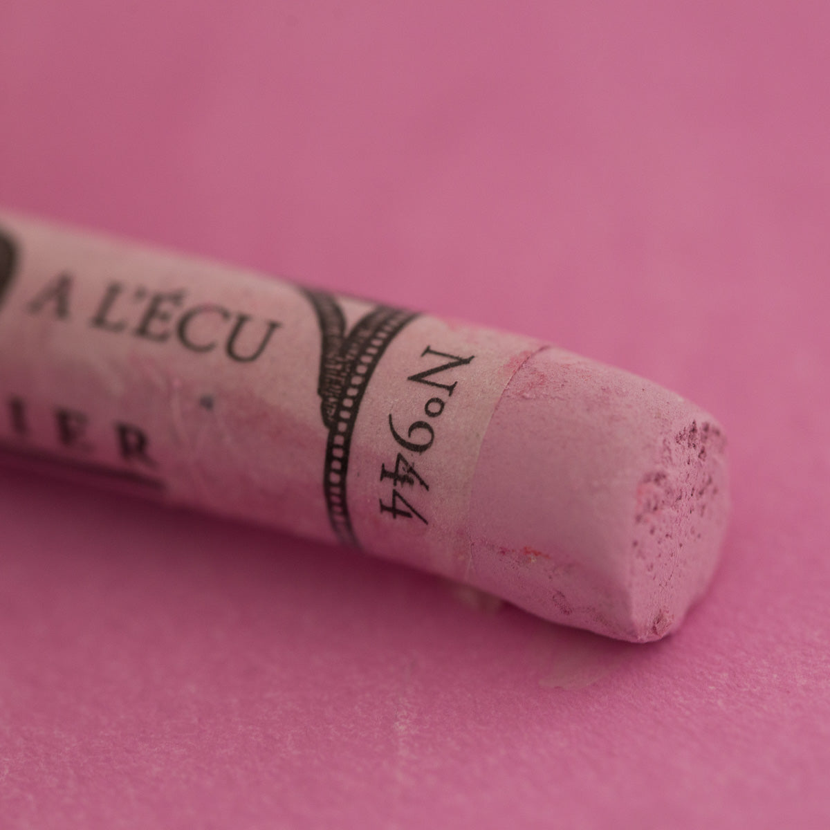 A close-up of a light purple Sennelier extra soft pastel. on the same coloured background, with the colour information printed on the paper wrap.