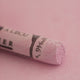 A close-up of a pale purple Sennelier extra soft pastel. on the same coloured background, with the colour information printed on the paper wrap.