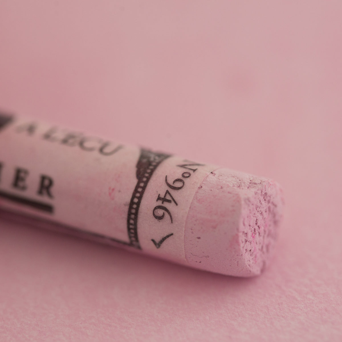 A close-up of a pale purple Sennelier extra soft pastel. on the same coloured background, with the colour information printed on the paper wrap.