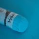 A close-up of a Sennelier blue extra soft pastel. on the same coloured background, with the colour information printed on the paper wrap.