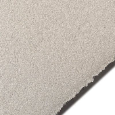 A close-up image of a piece of BFK Rives printmaking paper in a light grey colour, showing its texture and deckle edge.
