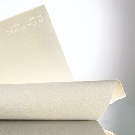 A rolled piece of BFK Rives printmaking paper, with part of the paper sheet visible, showing a smooth, light grain surface and a watermark with a watermark reading ' BFK Rives France' and an infinity symbol.