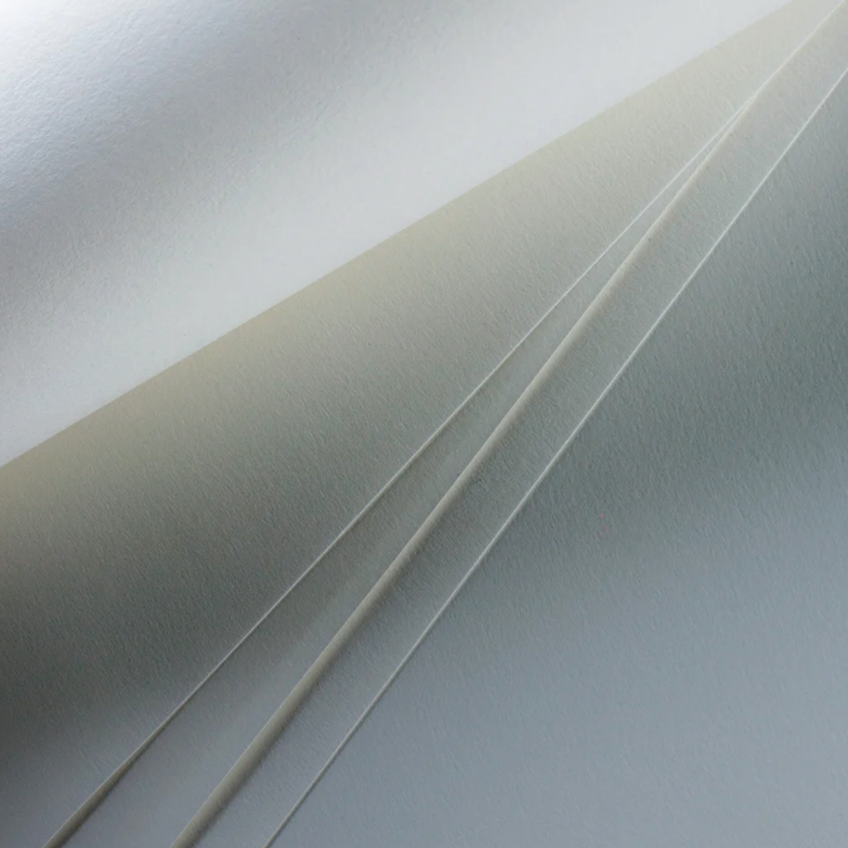 Stacked sheets of white drawing paper showing the natural soft grain texture.