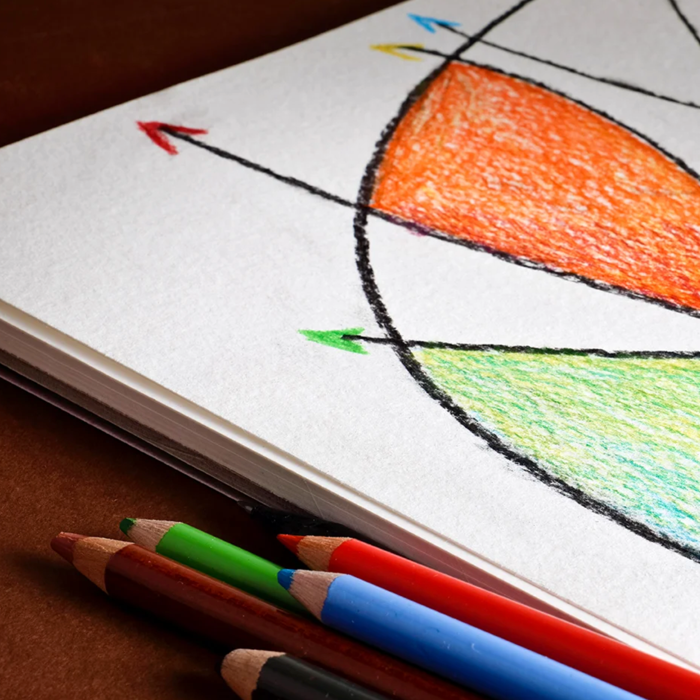 A drawing pad with a drawing that uses various colors, accompanied by colored pencils on the side.