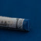 A close-up of a Sennelier large extra soft pastel on a dark blue background.