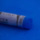 A close-up of a Sennelier large extra soft pastel on a bright blue background.