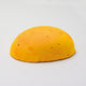 A half egg shaped pastel in a bright warm yellow, sitting on a white background