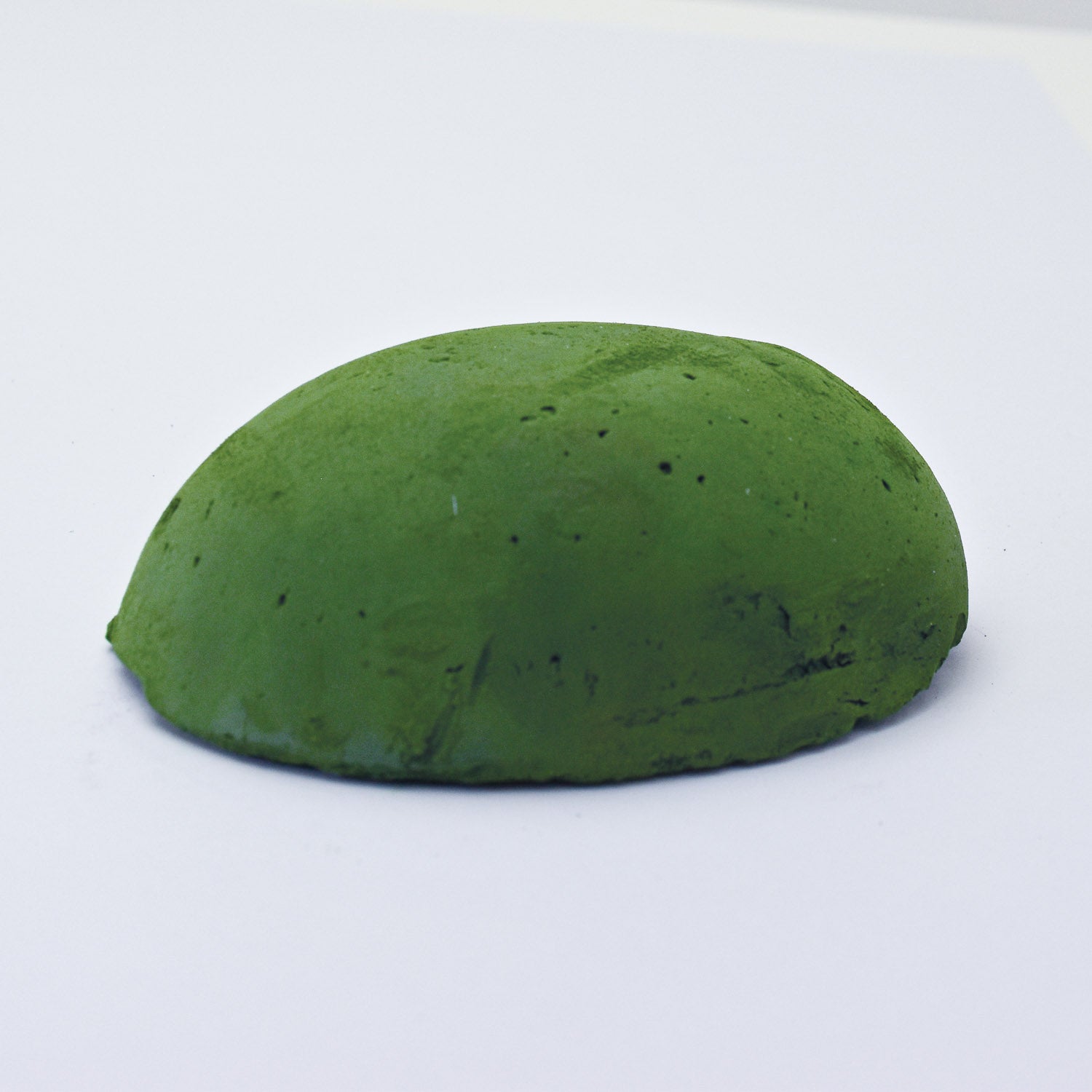 A half egg shaped pastel in an Olive Green sitting on a white background