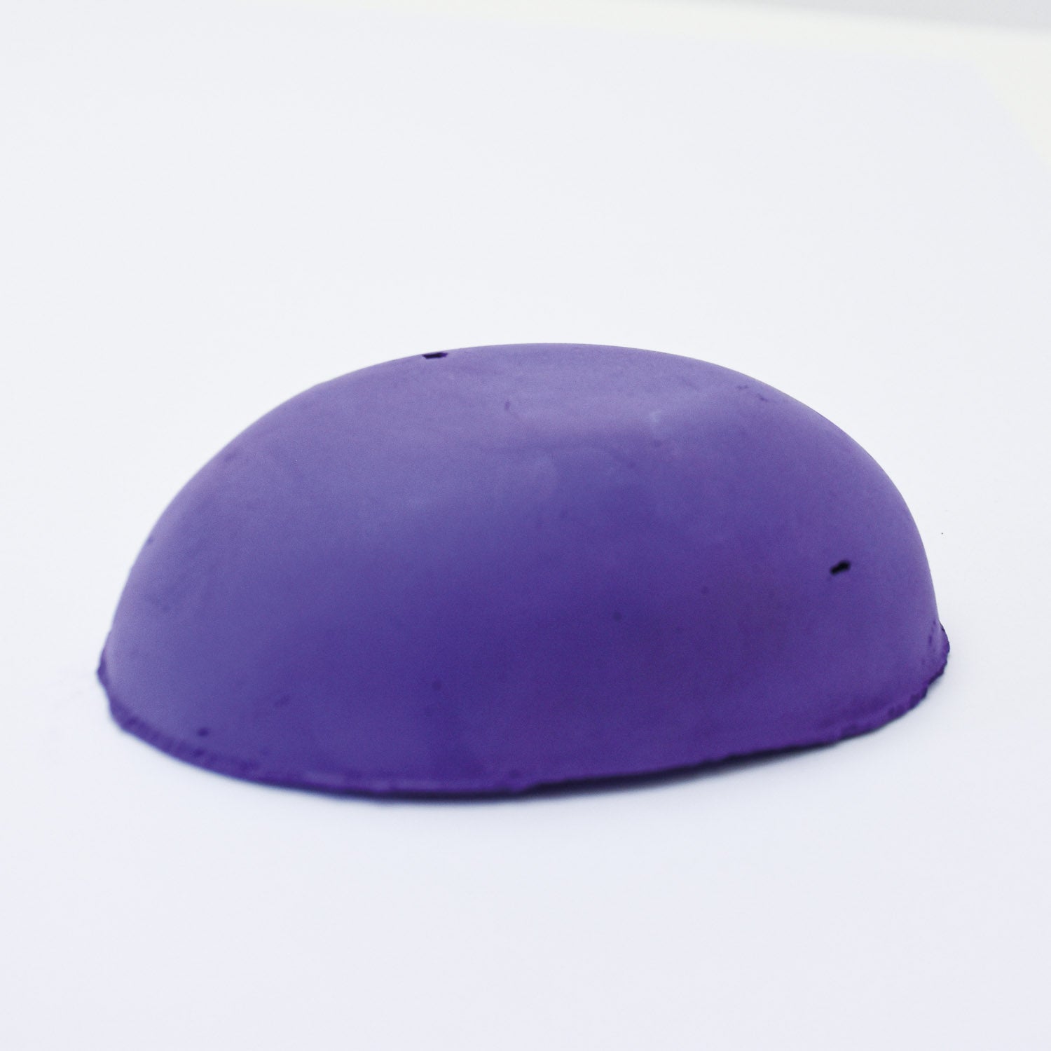 A half egg shaped pastel in a cool blue-purple tone, sitting on a white background