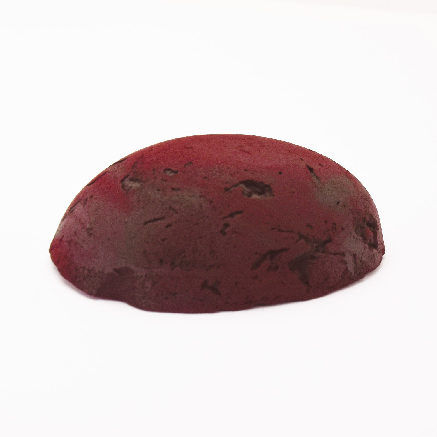 A half egg shaped pastel in a red-brown tone, sitting on a white background