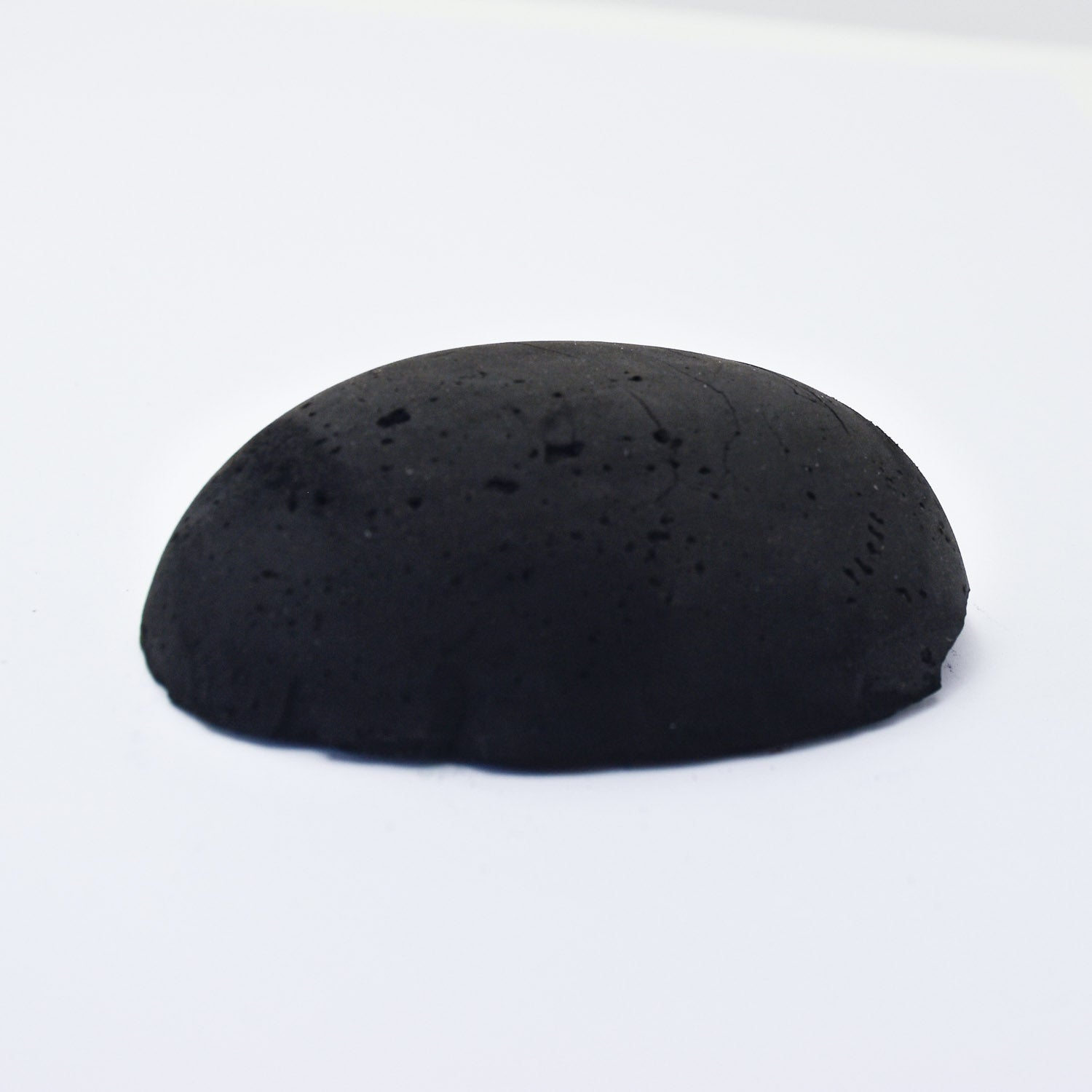 A half egg shaped pastel in a black tone, sitting on a white background