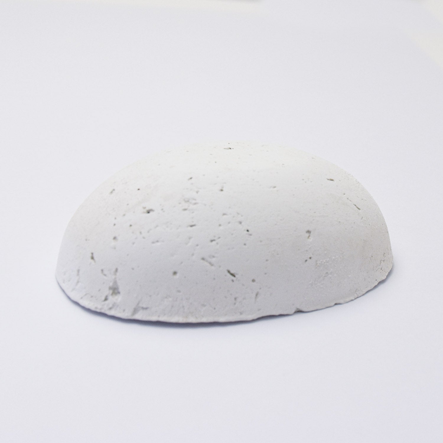 A half egg shaped pastel in a white tone, sitting on a white background