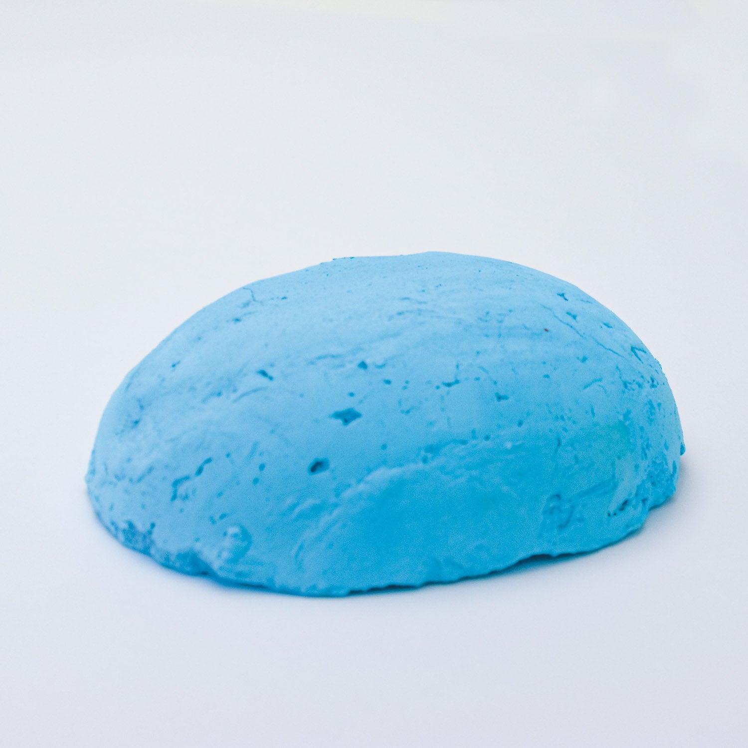 A half egg shaped pastel in a light blue tone, sitting on a white background