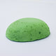 
A half egg shaped pastel in a bright green tone, sitting on a white background