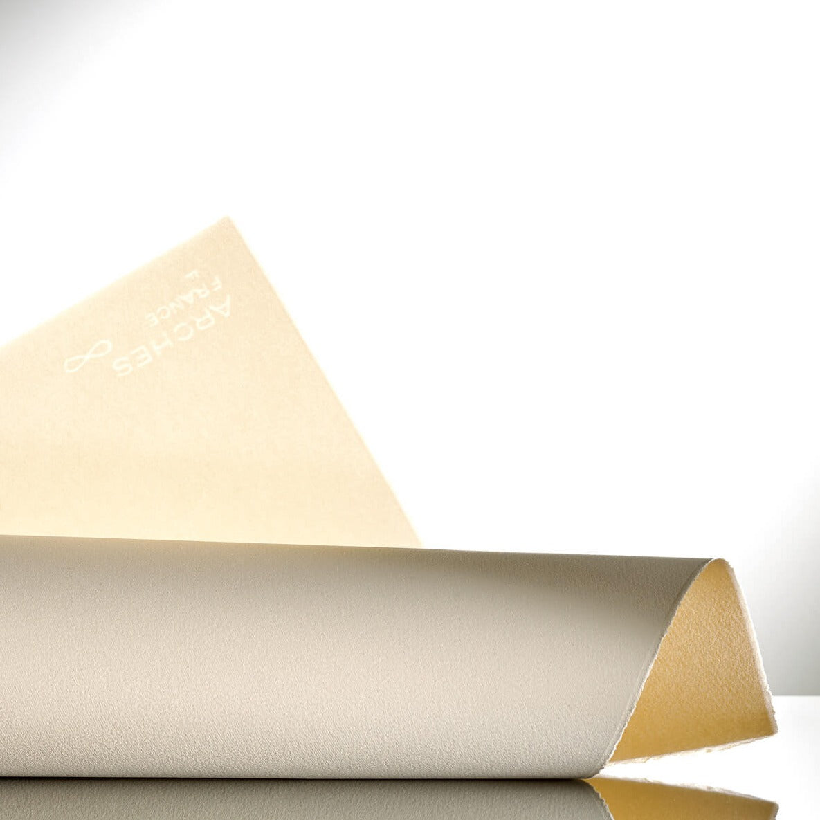 A roll of Velin Arches 300gsm drawing and printmaking paper, partially unrolled to show the fine grain and watermark, placed on a reflective surface.