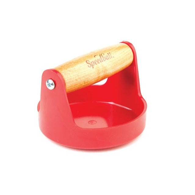 A red Speedball 4 inch plastic baren with a wooden handle, used for block printing and crafting.