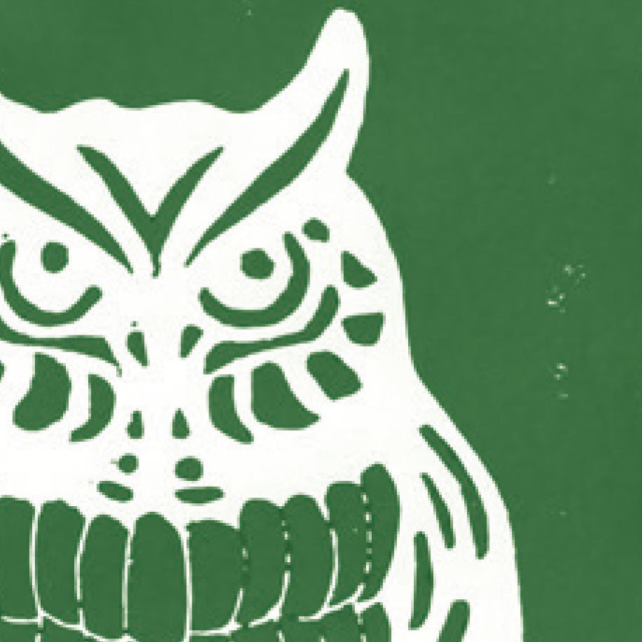 A printed linocut of an owl in green ink with the outline of the owl appearing in white.