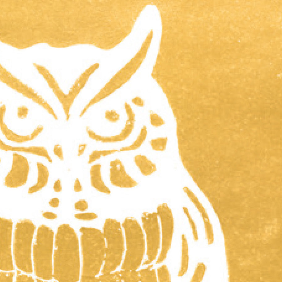A printed linocut of an owl in gold ink with the outline of the owl appearing in white.