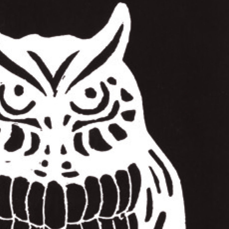 A printed linocut of an owl in black ink with the outline of the owl appearing in white.