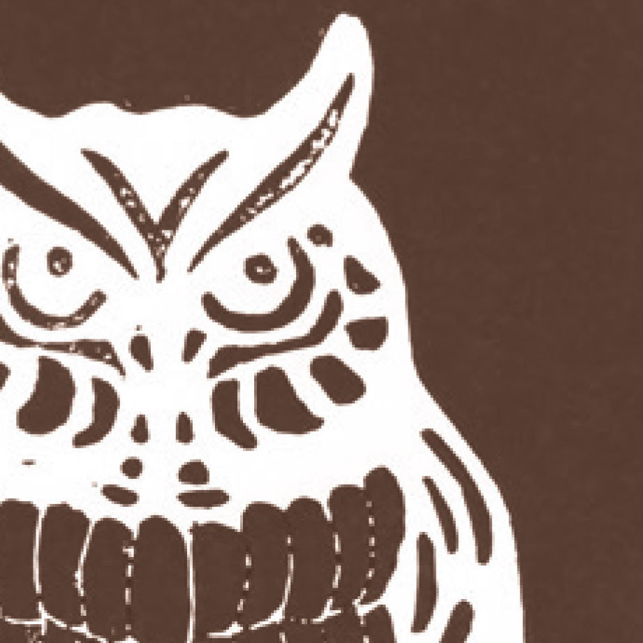 A printed linocut of an owl in brown ink with the outline of the owl appearing in white.