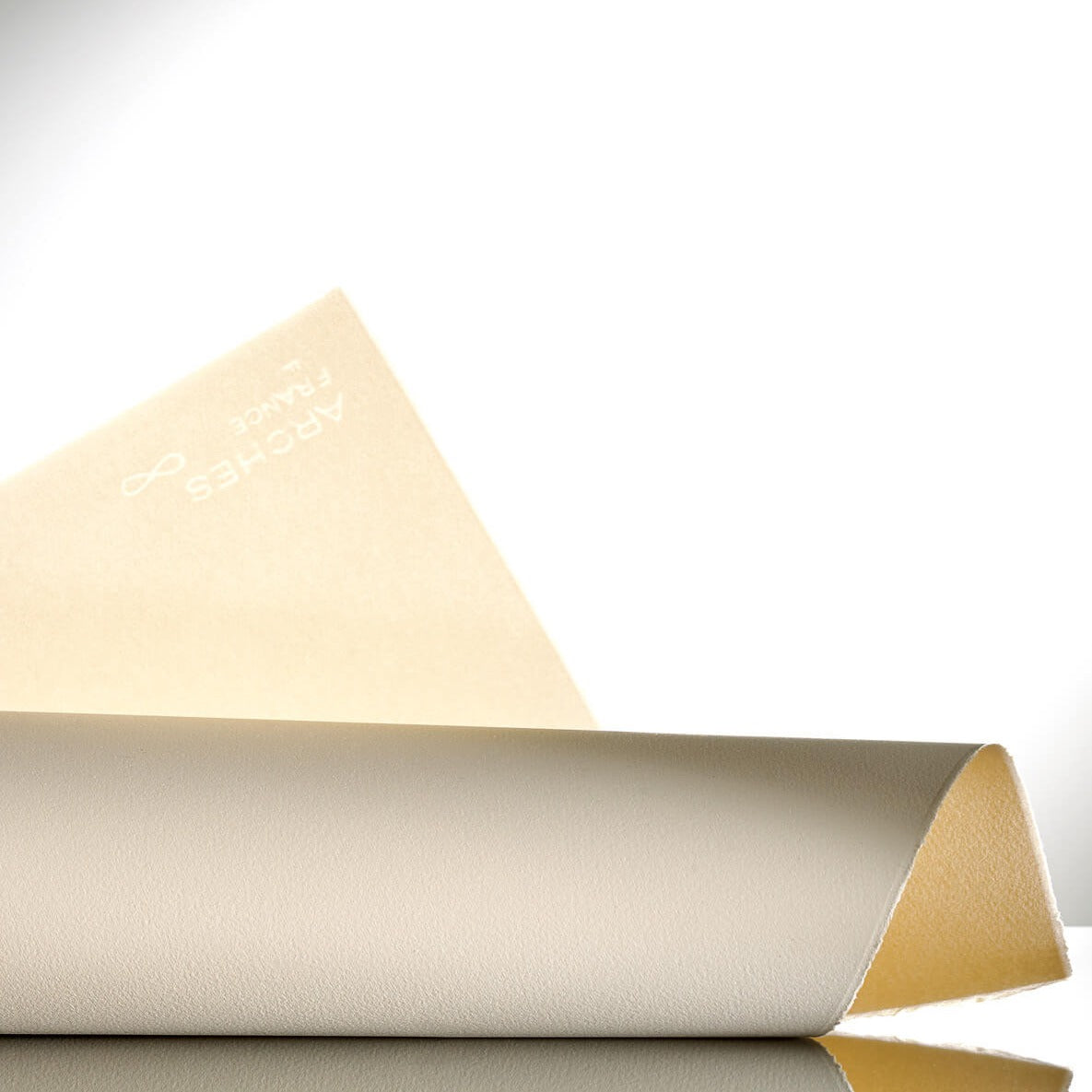 A roll of Velin Arches 300gsm drawing and printmaking paper, partially unrolled to show the fine grain and watermark, placed on a reflective surface.
